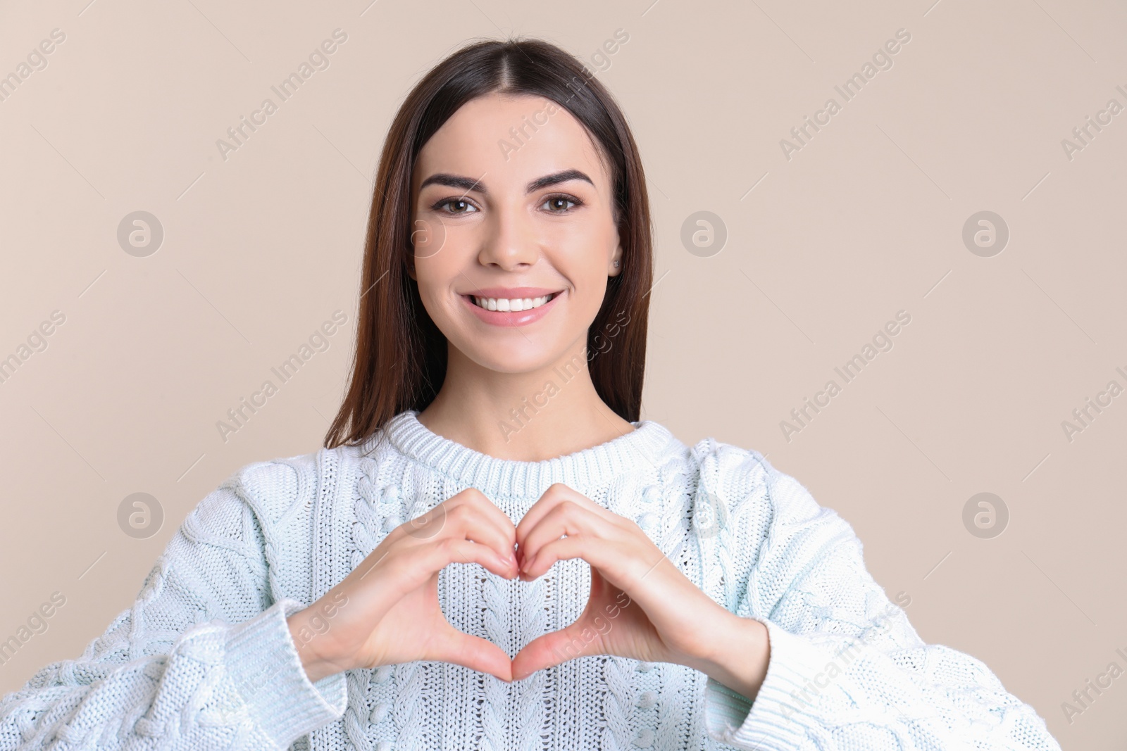 Photo of Portrait of young woman making heart with her hands on color background