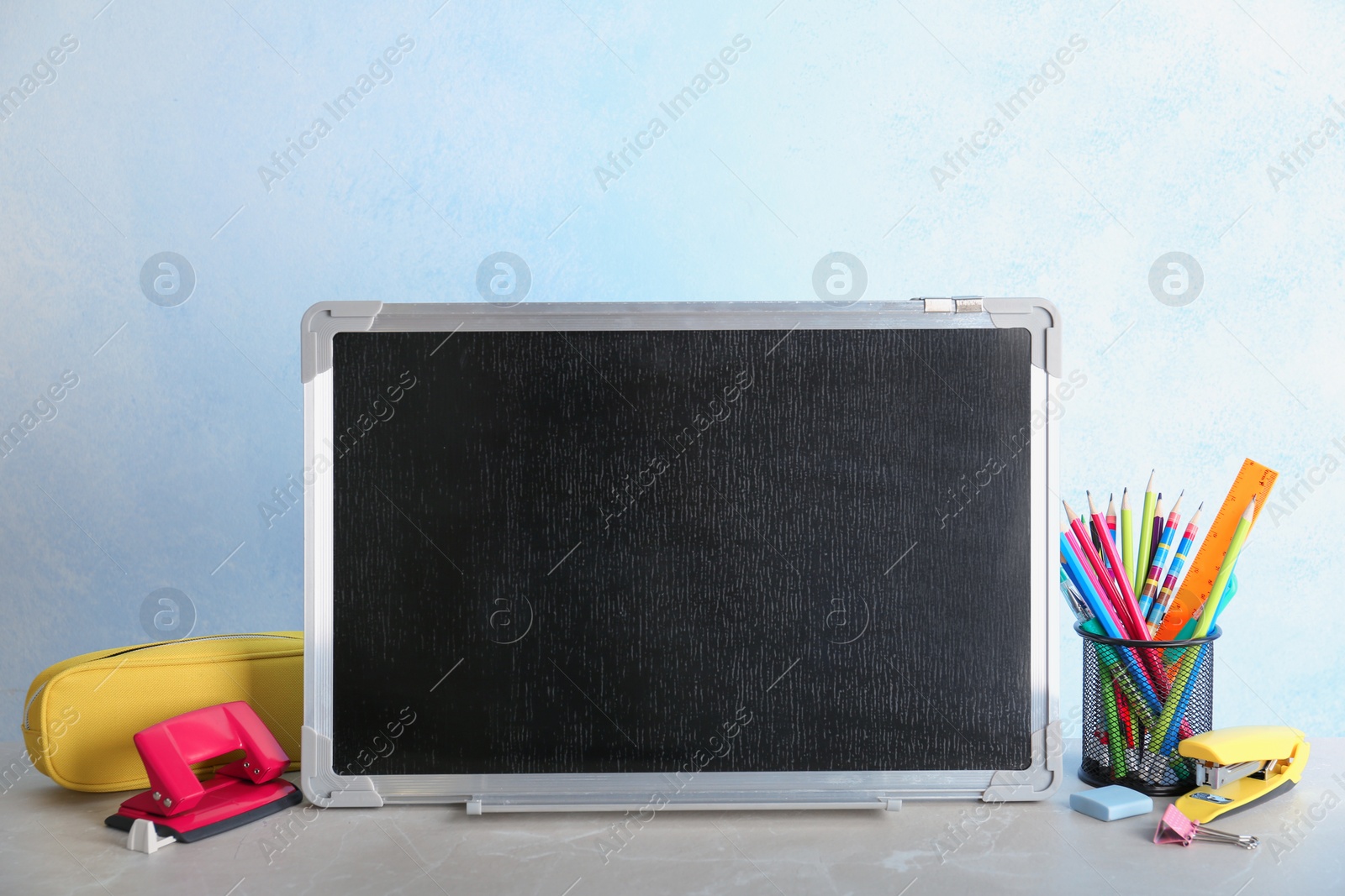 Photo of Small chalkboard and different school stationery on table