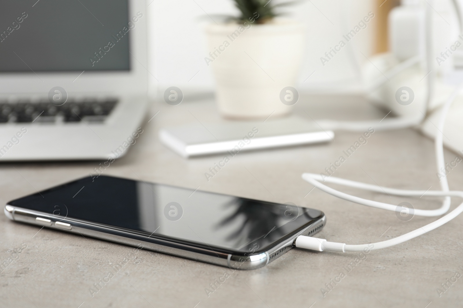 Photo of Smartphone charging with cable on light stone table