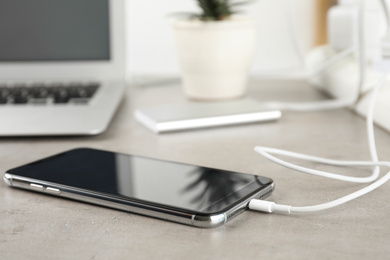 Smartphone charging with cable on light stone table
