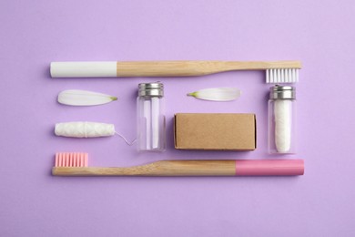 Photo of Flat lay composition with sustainable dental flosses and bamboo toothbrushes on violet background