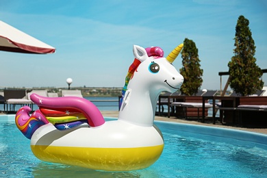 Photo of Funny inflatable unicorn ring floating in swimming pool on sunny day, outdoors