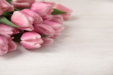 Photo of Beautiful pink spring tulips on white wooden background, closeup. Space for text