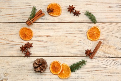 Photo of Frame made of dry orange slices, cinnamon sticks, fir branches and anise stars on white wooden table, flat lay with space for text