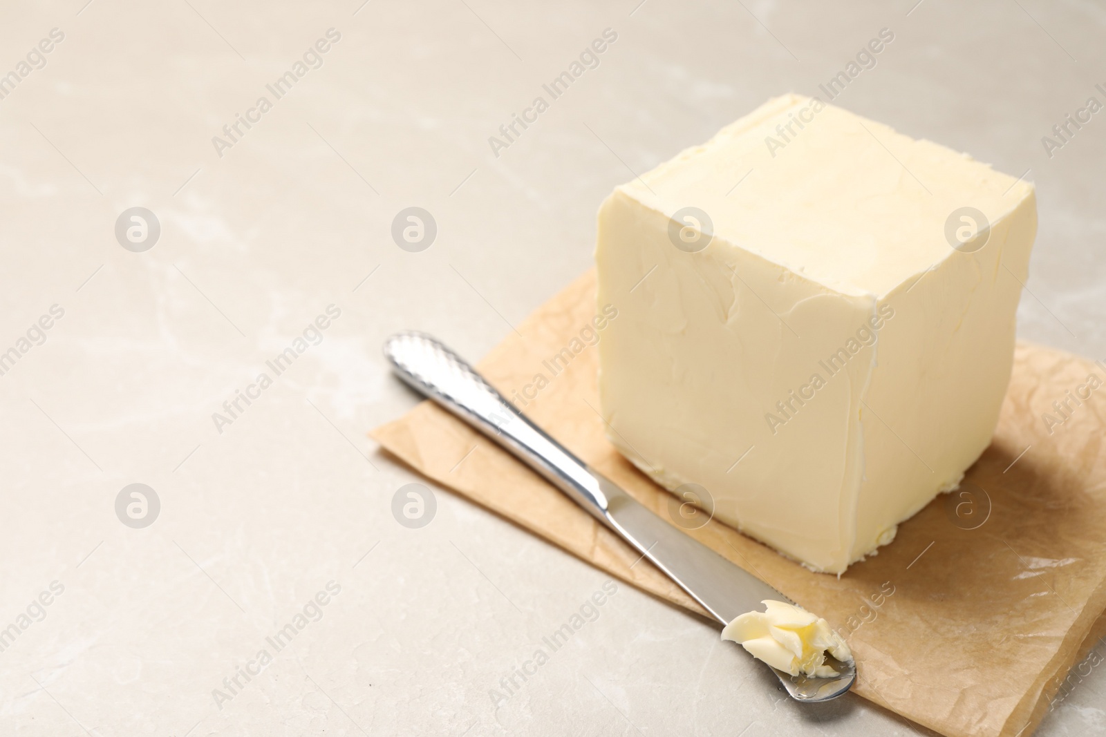 Photo of Block of tasty butter and knife on light table. Space for text