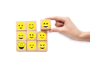 Woman holding cube with smiling face among other with emoticons on white background, top view