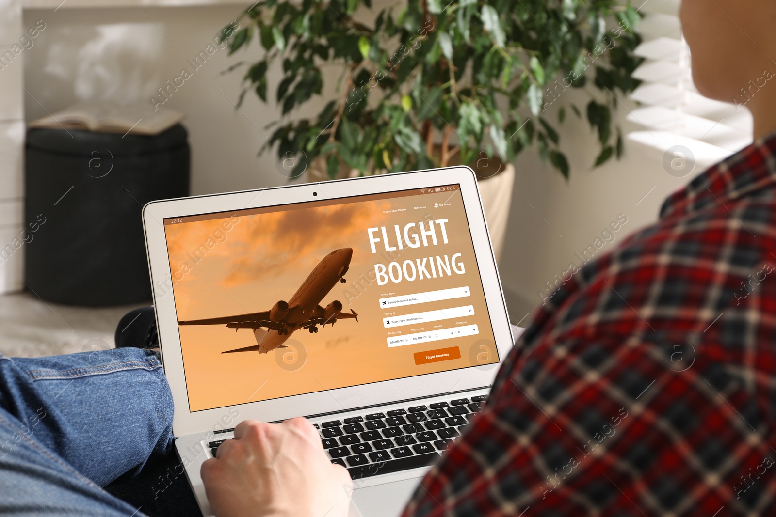 Image of Man using laptop to book flight at home, closeup