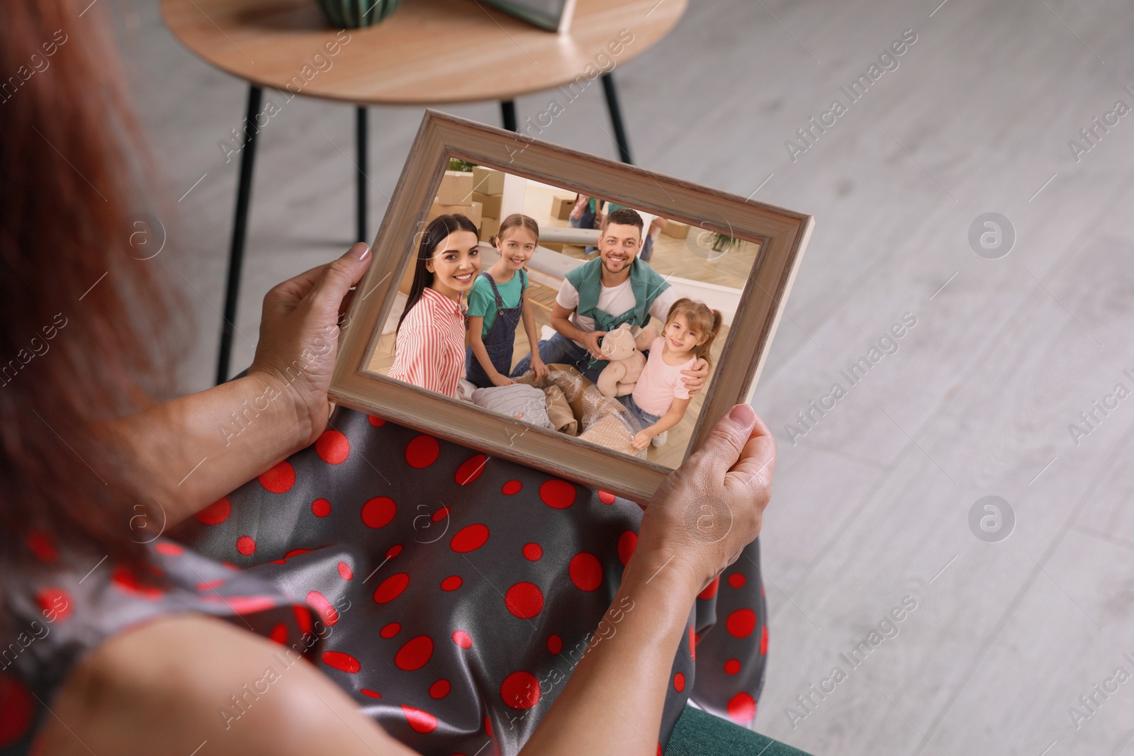 Image of Woman holding frame with photo portrait of her family indoors, closeup