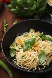 Photo of Delicious pasta primavera with basil, broccoli and peas on table, closeup