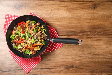 Stir-fry. Tasty noodles with meat and vegetables in wok on wooden table, top view