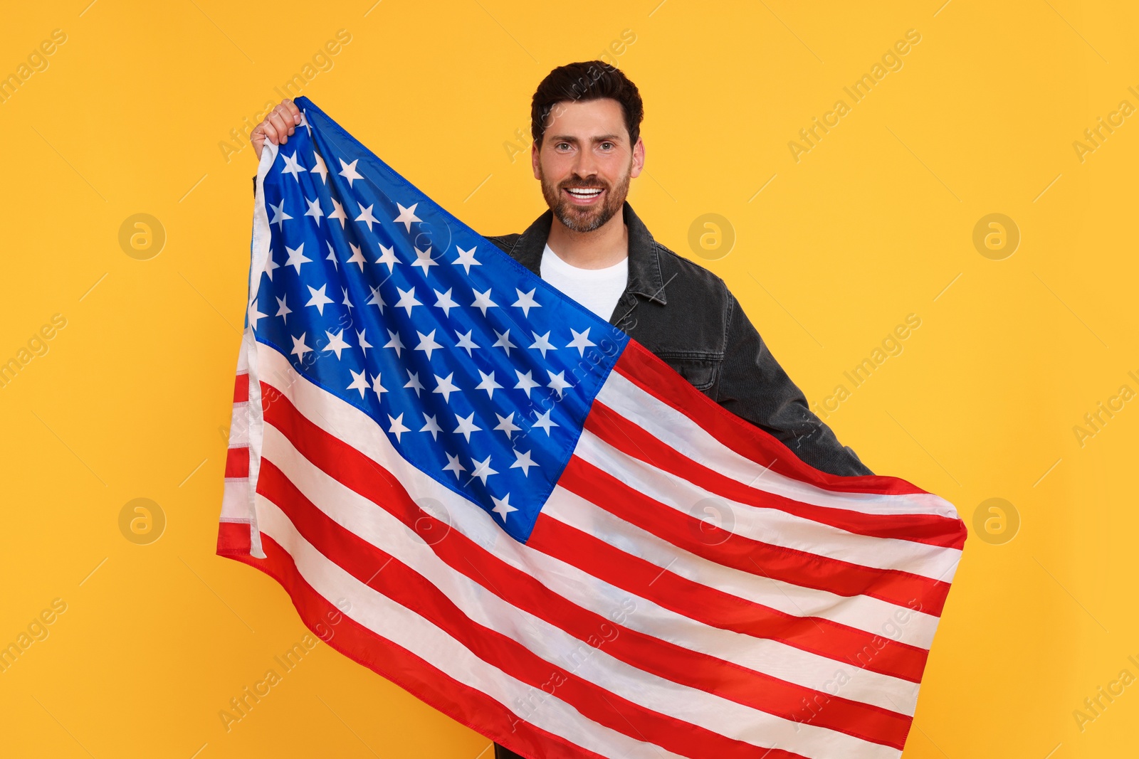 Photo of 4th of July - Independence Day of USA. Happy man with American flag on yellow background