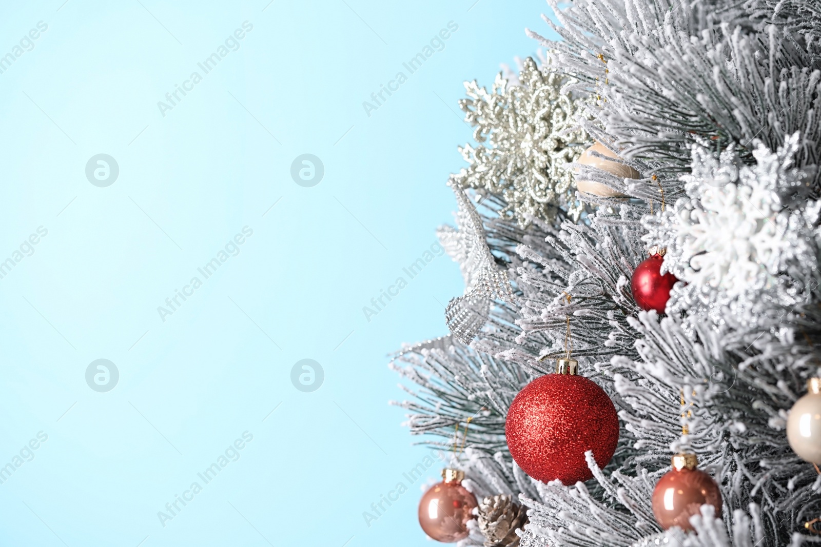 Photo of Beautiful Christmas tree with festive decor on light blue background. Space for text