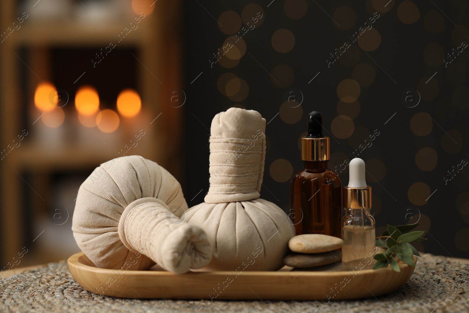 Photo of Spa composition. Herbal sacks, cosmetic products and stones on table indoors