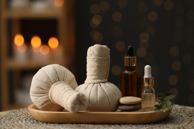 Photo of Spa composition. Herbal sacks, cosmetic products and stones on table indoors