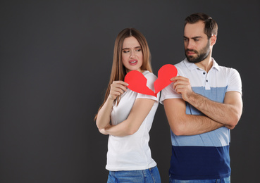 Photo of Couple with torn paper heart on black background. Relationship problems