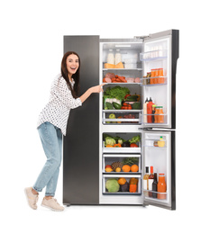 Photo of Young woman near open refrigerator on white background