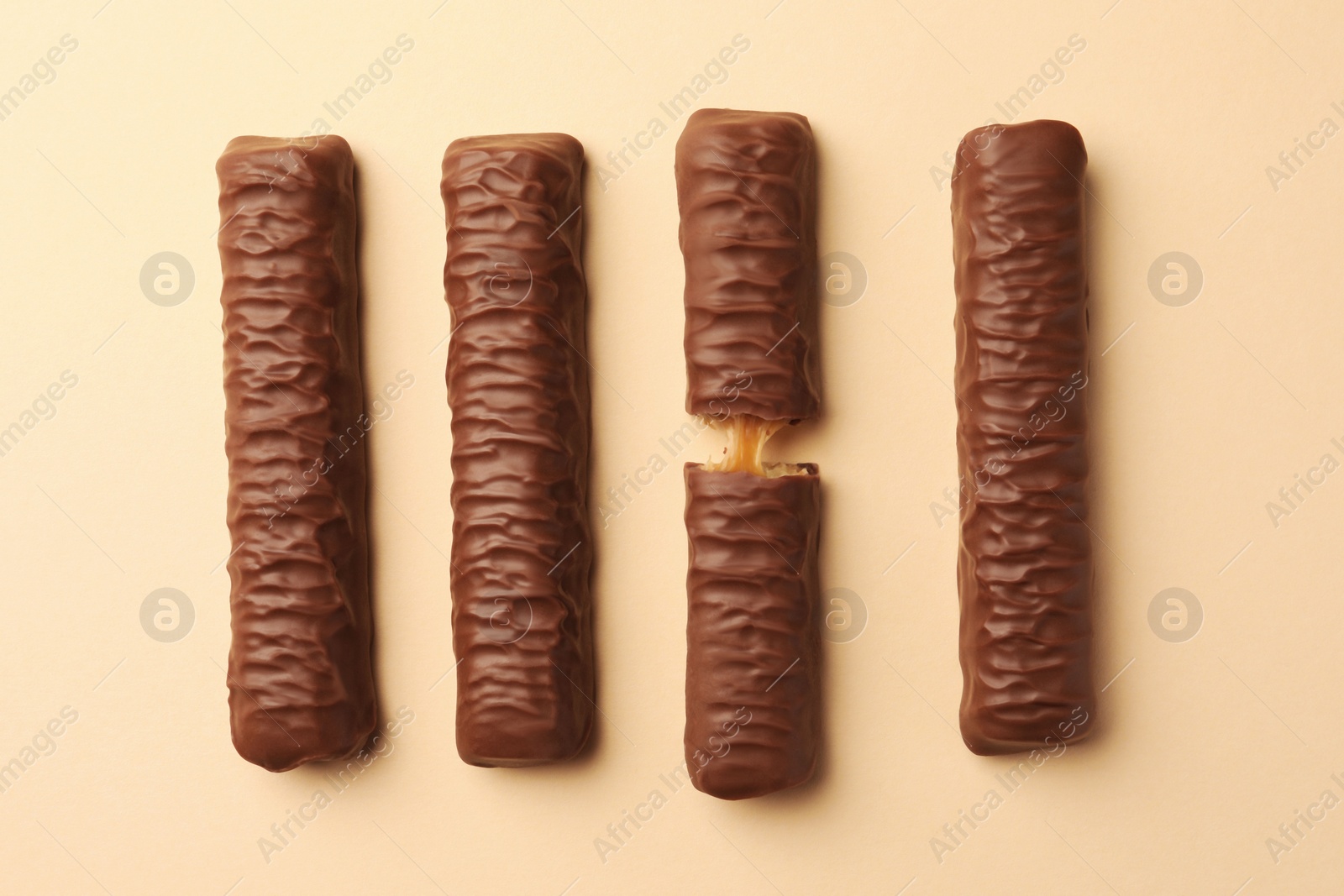 Photo of Sweet tasty chocolate bars with caramel on beige background, flat lay