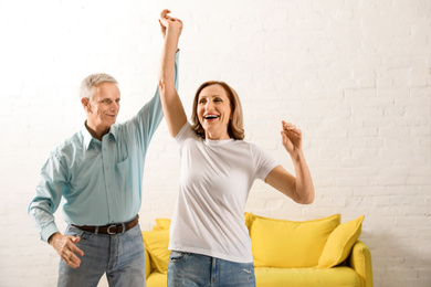 Photo of Happy senior couple dancing in living room