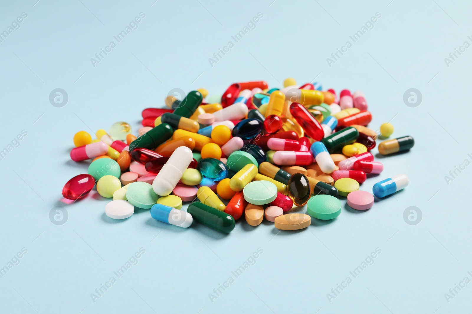 Photo of Many different pills on light blue background