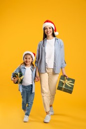 Photo of Mother and daughter with Christmas gifts on yellow background