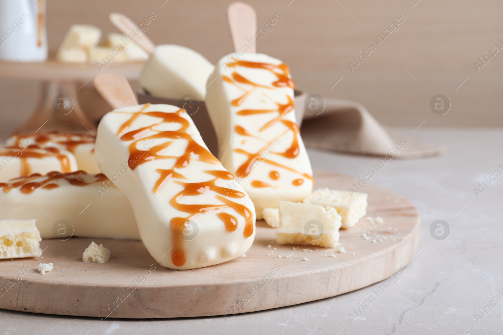 Photo of Delicious glazed ice cream bars and chocolate on light grey marble table