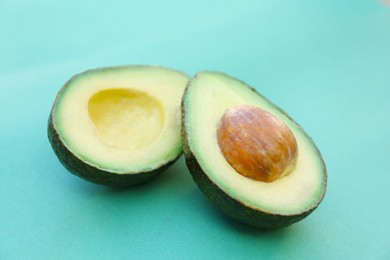 Photo of Tasty cut avocado on turquoise background, closeup