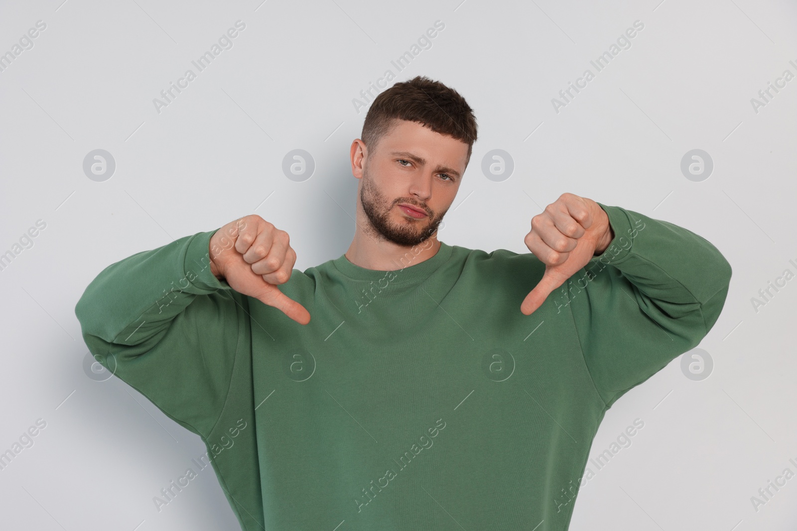 Photo of Young man showing thumbs down on white background