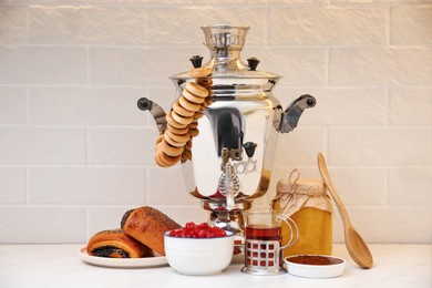 Photo of Traditional Russian samovar and treats on white table