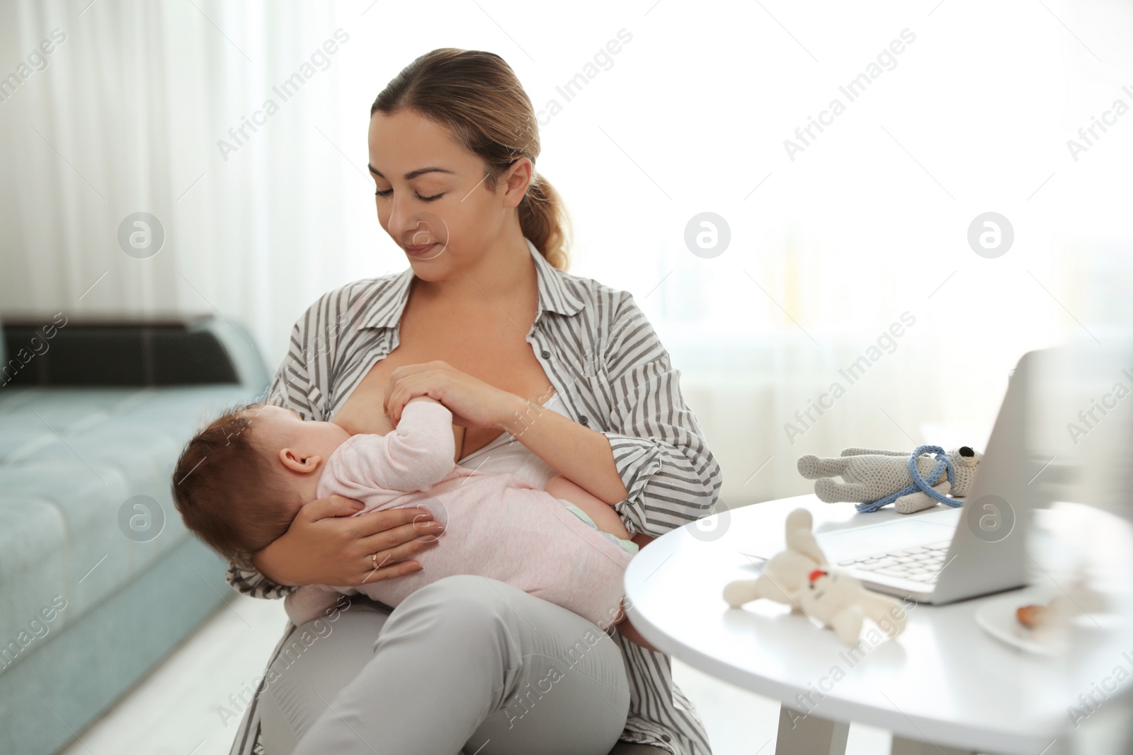 Photo of Young woman breastfeeding her baby at home