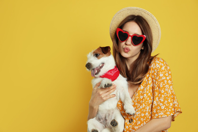 Photo of Young woman with her cute Jack Russell Terrier on yellow background, space for text. Lovely pet