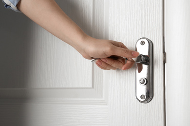 Photo of Woman opening white wooden door indoors, closeup