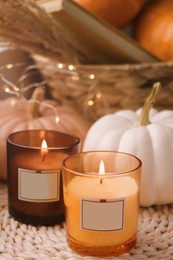 Scented candles and pumpkins on wicker mat indoors