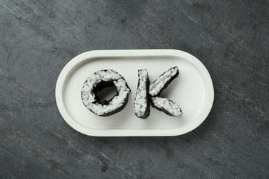 Photo of Word Ok made of sushi rolls on dark grey table, top view