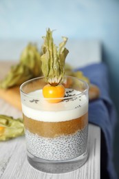 Delicious chia pudding decorated with physalis fruit on white wooden table