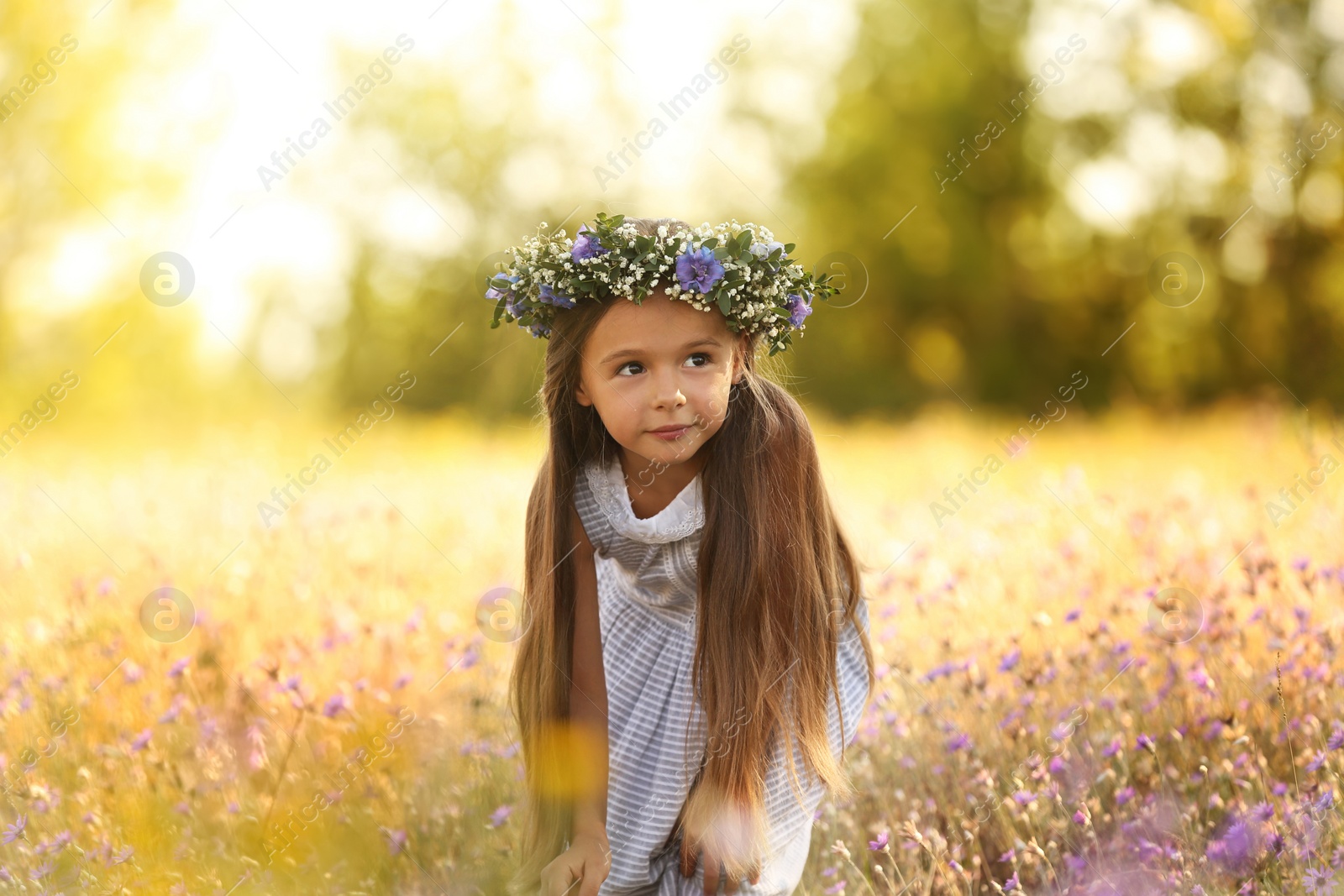 Photo of Cute little girl wearing flower wreath outdoors. Child spending time in nature