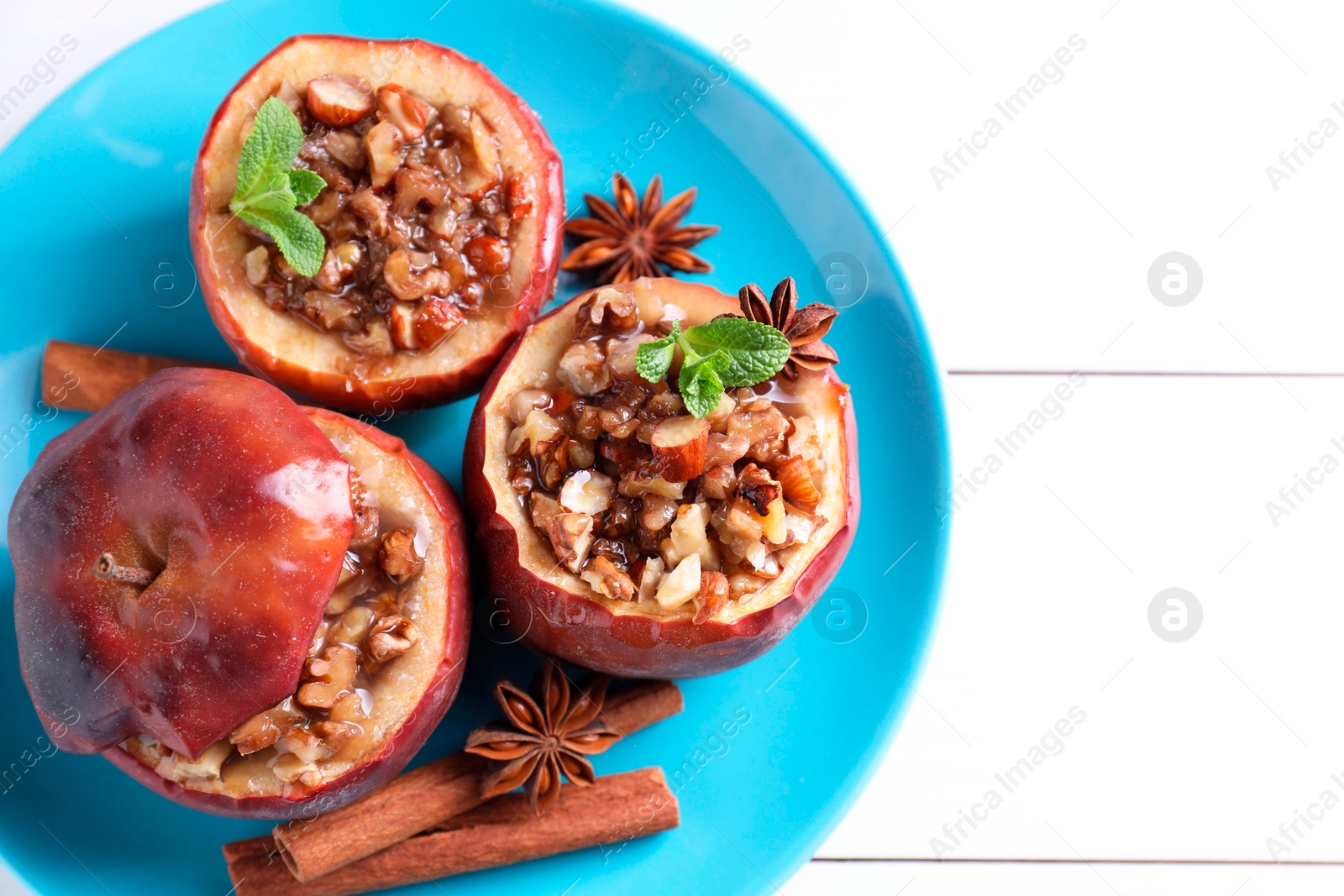 Photo of Tasty baked apples with nuts, honey, spices and mint on white wooden table, top view