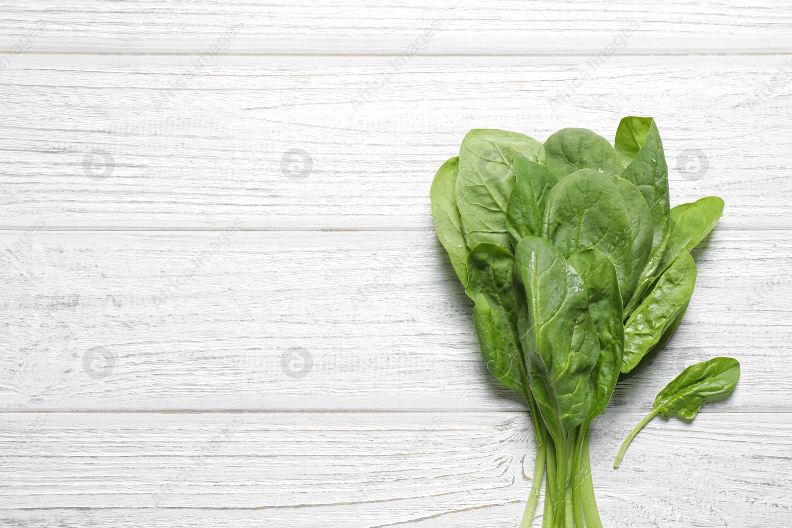 Photo of Fresh green healthy spinach on white wooden table, top view. Space for text