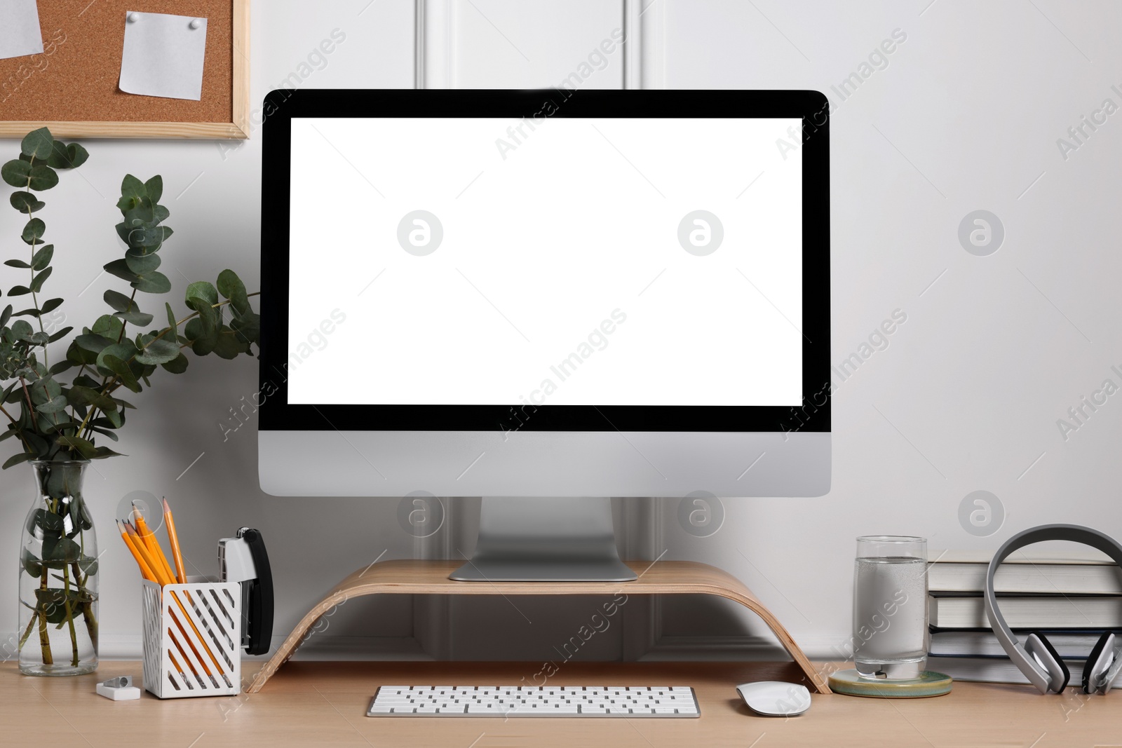 Photo of Cozy workspace with computer, headphones and stationery on wooden desk