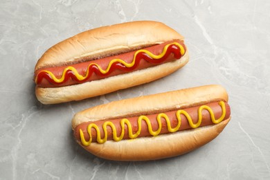 Photo of Delicious hot dog with mustard and ketchup on light grey table, flat lay