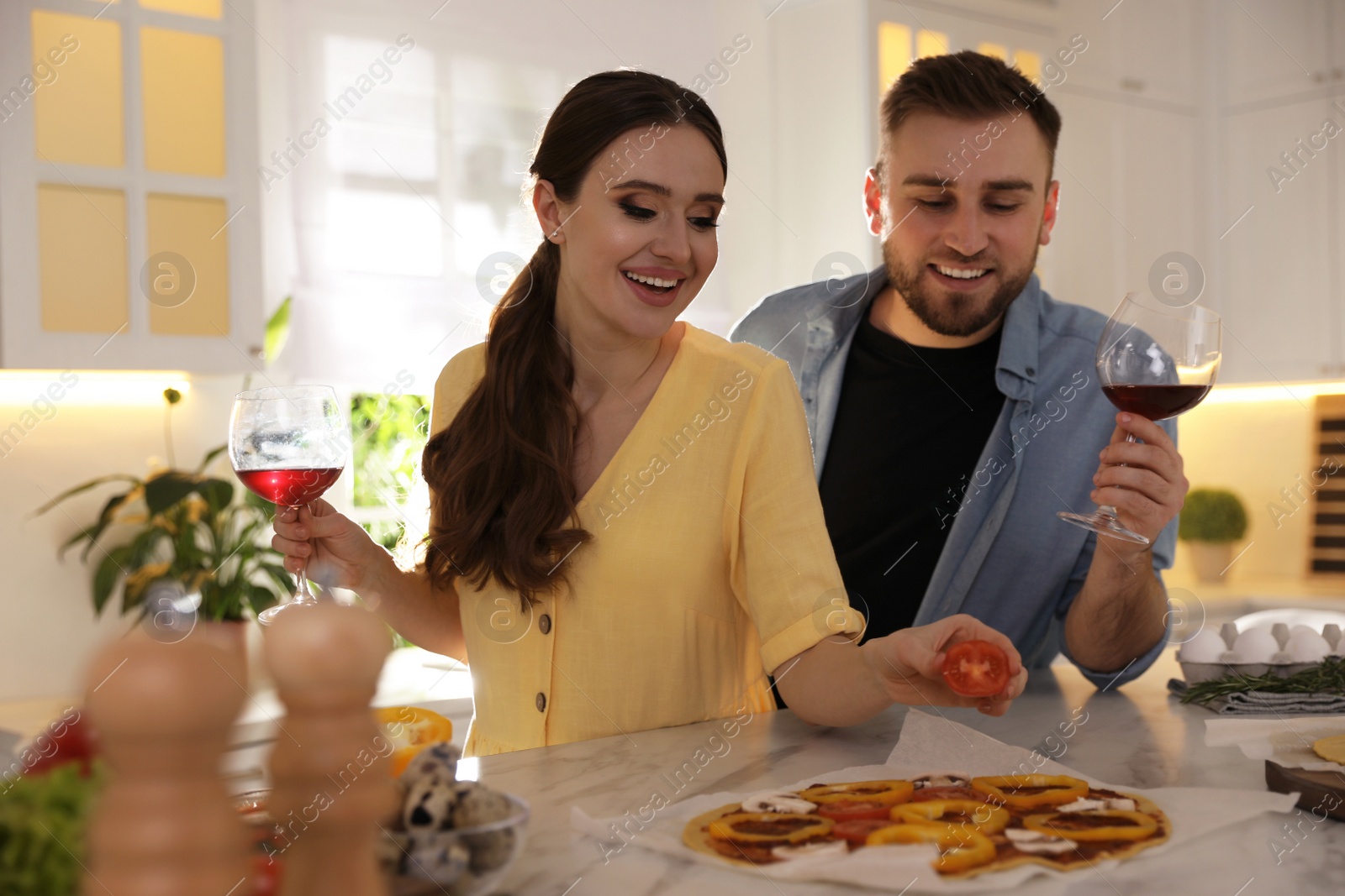 Photo of Lovely young couple cooking pizza together in kitchen