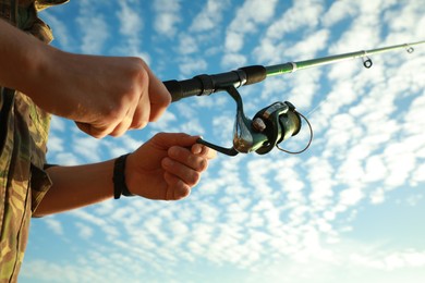 Photo of Fisherman with rod fishing under blue sky, closeup