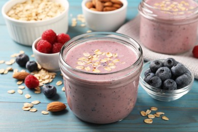 Photo of Tasty berry smoothie with oatmeal on light blue wooden table