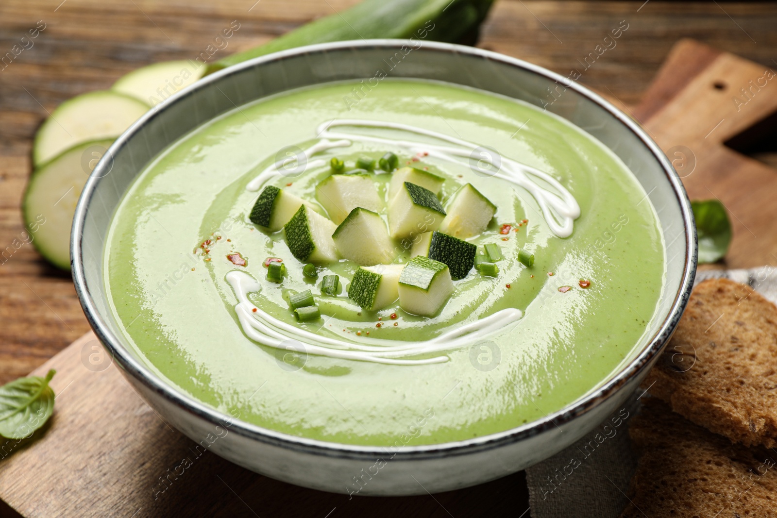 Photo of Tasty homemade zucchini cream soup in bowl, closeup