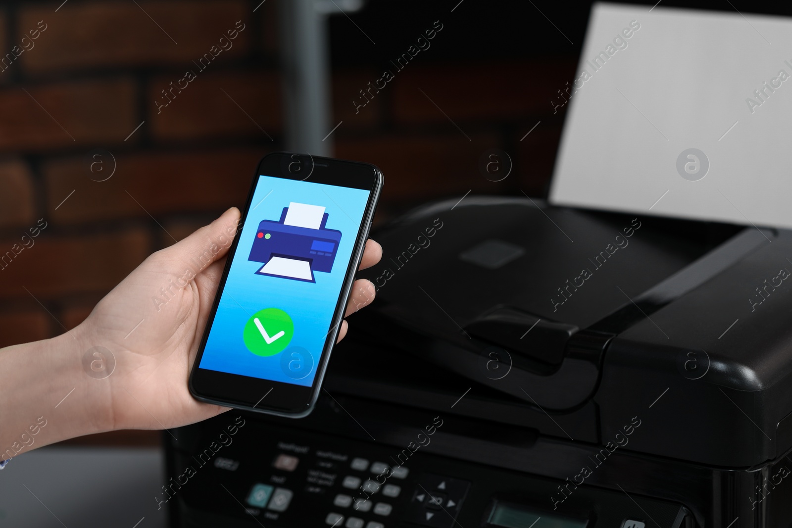 Photo of Man using printer management application on mobile phone indoors, closeup. Image on device screen.
