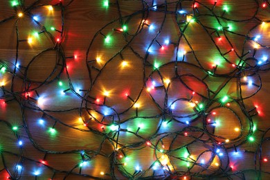 Photo of Colorful Christmas lights on wooden table, top view