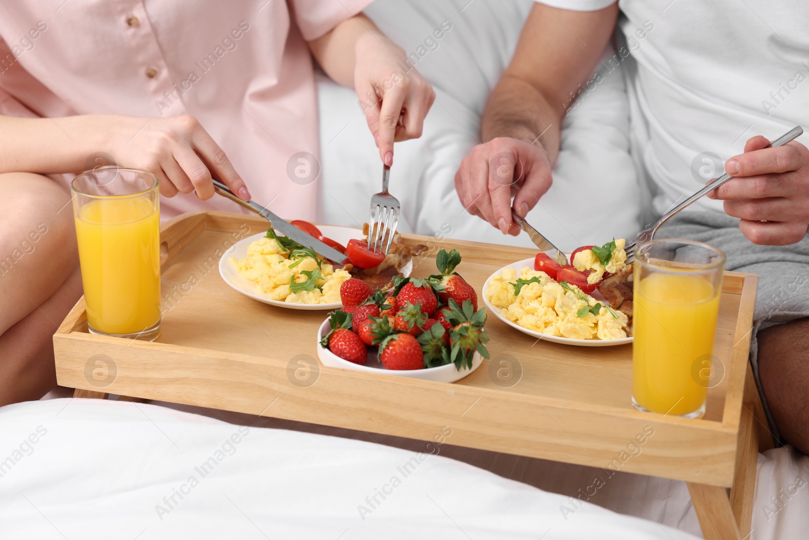 Photo of Couple eating tasty breakfast on bed, closeup