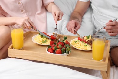 Photo of Couple eating tasty breakfast on bed, closeup