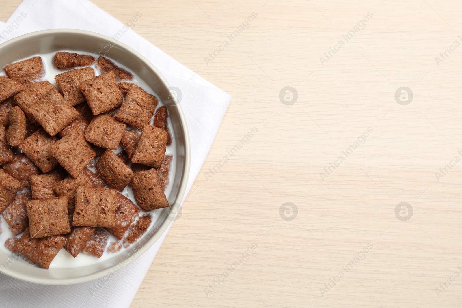 Photo of Bowl with tasty corn pads and milk on wooden table, flat lay. Space for text