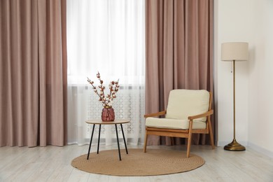 Photo of Living room with pastel window curtains, wooden table and armchair