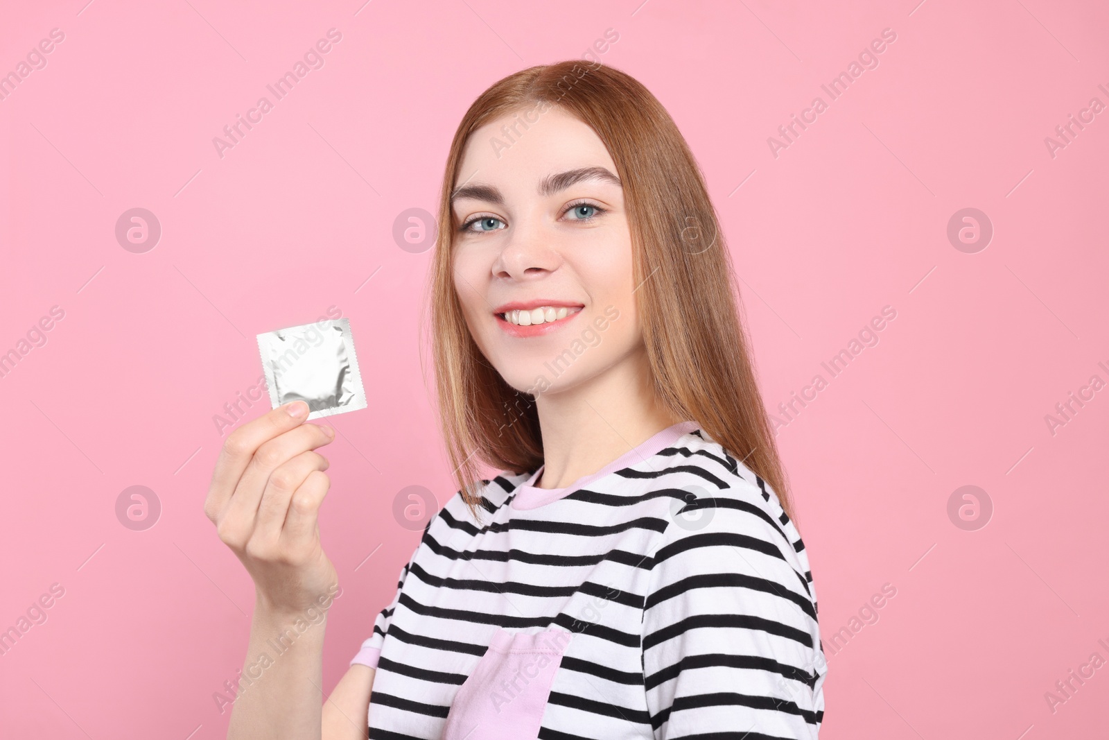 Photo of Woman holding condom on pink background. Safe sex